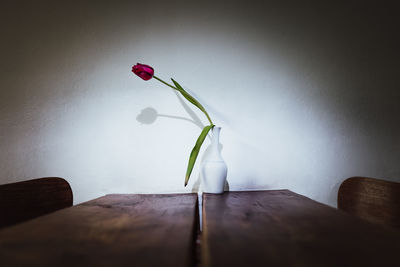 Flower vase on table against wall at home