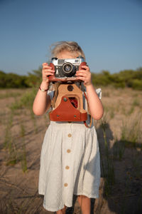 Portrait of man photographing camera on field