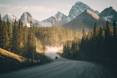 Road by rocky mountains against sky