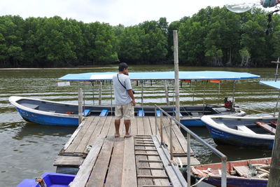 Rear view of man standing on boat in lake