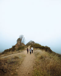 Rear view of men on mountain against sky