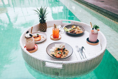 Breakfast on floating table in the pool. healthy food with smoothie and pineapple.