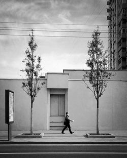 Man walking on road by building in city