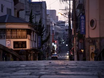 Street amidst buildings in city at dusk