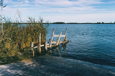 Empty chairs by sea against sky