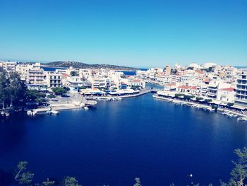 High angle view of buildings by sea against clear blue sky