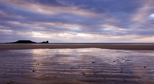 Scenic view of beach against cloudy sky