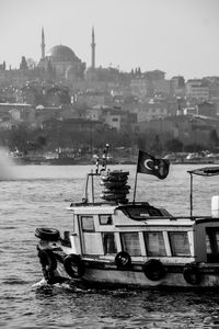 Boats moored at harbor in city against sky