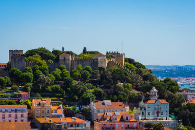 Buildings by sea against clear blue sky