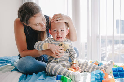 Mother hugging pacifying sad upset crying toddler boy. family young mom and crying baby 