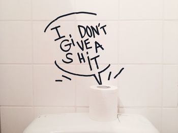 Text on wall with toilet paper in bathroom