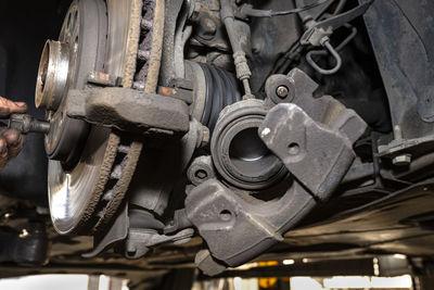 Disassembled front brake caliper on the car, which is on the car jack in the workshop.