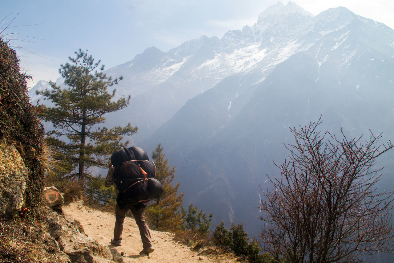 Rear view of man walking on mountain against sky