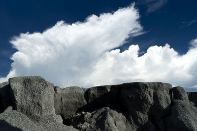 Low angle view of rocks against cloudy sky