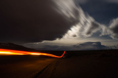 Light trails on highway against sky at night