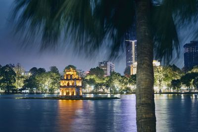 Illuminated building by river at night