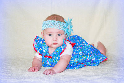 Portrait of cute baby girl lying on bed