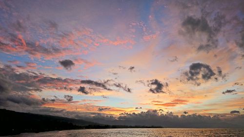 Scenic view of sea against cloudy sky at sunset