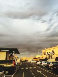 Cars on road against cloudy sky