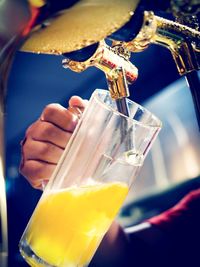 Close-up of hand pouring drink in glass from machinery