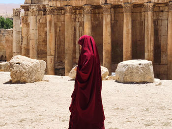 Rear view of woman standing against stone wall