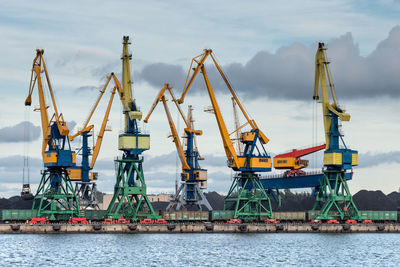 Cranes at commercial dock against sky