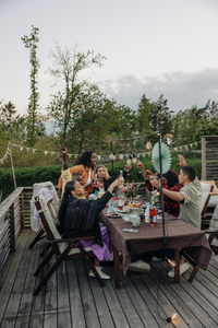 Multiracial male and female friends enjoying drinks while sitting at dining table