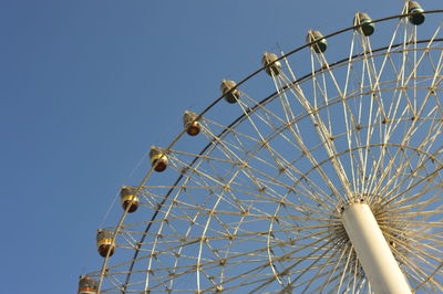 Low angle view of ferris wheel against clear blue sky