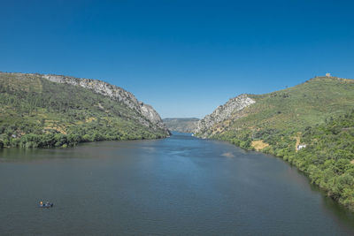 Scenic view of river amidst mountains against clear blue sky