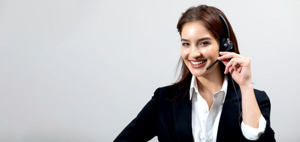 Smiling young woman using smart phone against white background