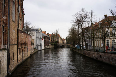 Canal amidst buildings against sky in city