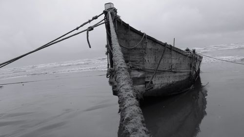 Fishing boat on beach against sky