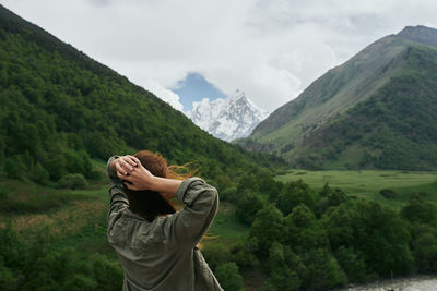 Rear view of man looking at mountain range against sky