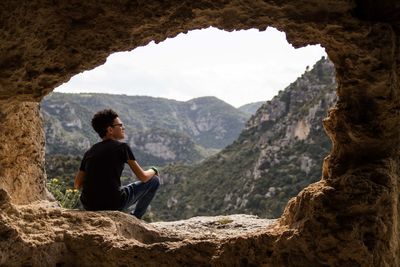 Man sitting on rock looking at mountains
