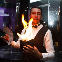 Portrait of waiter holding burning textile and cards at restaurant