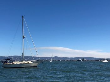 Sailboat sailing on sea against blue sky