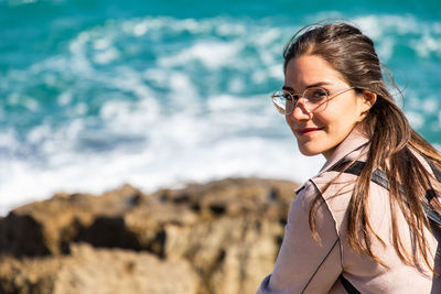 Portrait of smiling woman sitting on rock at beach