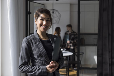 Portrait of confident female real estate agent holding folder at home