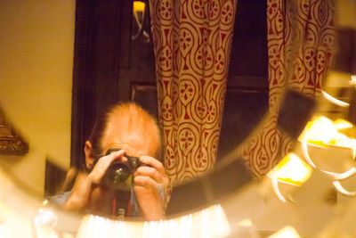 Portrait of man photographing illuminated smart phone