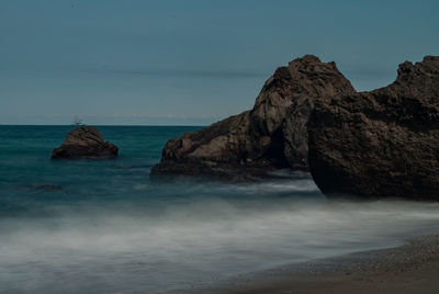 Rock formations in sea against sky