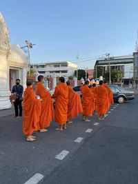 Rear view of people on street against orange sky