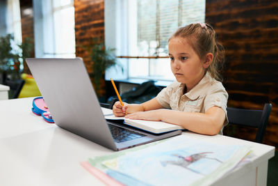 Absorbed student doing her homework using laptop at primary school. back to school. using technology