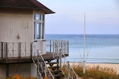 Stilt house on beach against sky
