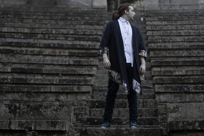 Young man looking away while standing on steps 