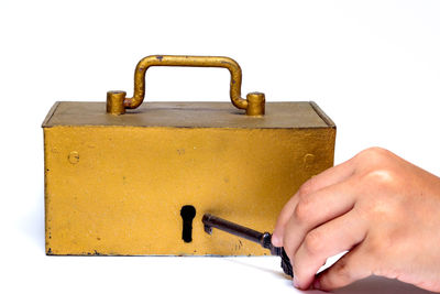 Close-up of human hand holding metal against white background