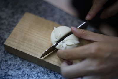 Cropped hands of woman cutting sweet food with knife