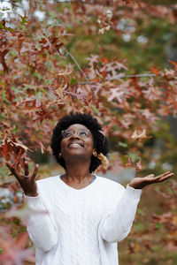 Portrait of smiling young woman standing against plants