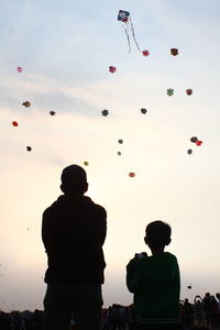 Low angle view of silhouette people standing against sky during sunset