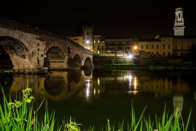 Illuminated bridge over river in city at night