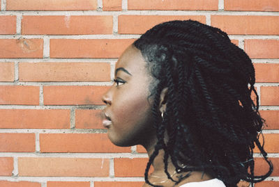 Close-up of young woman with dreadlocks against wall